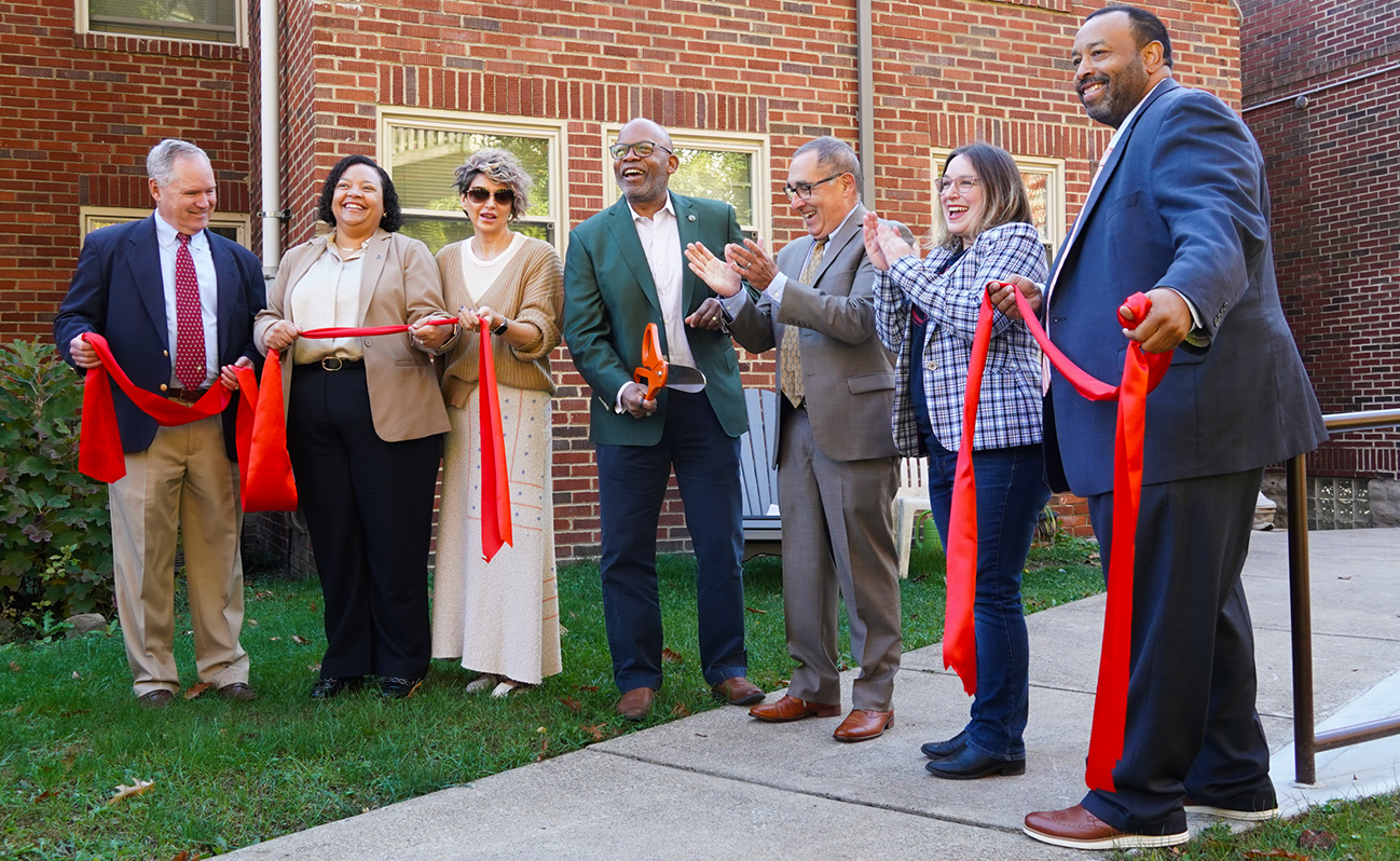seven people in business attire performing a ribbon cutting ceremony